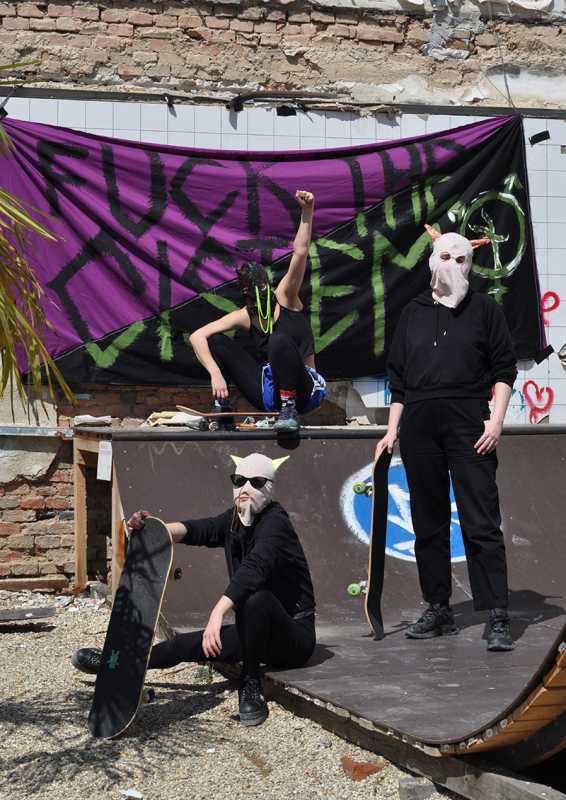 WIENWOCHE 2023: GIVE WAY, DARLING, GIVE WAY! Three members of the project team wearing masks, posing with skateboards in front of the slogan Fuck the CISTEM! © GORGON*URBAN & Moisturride