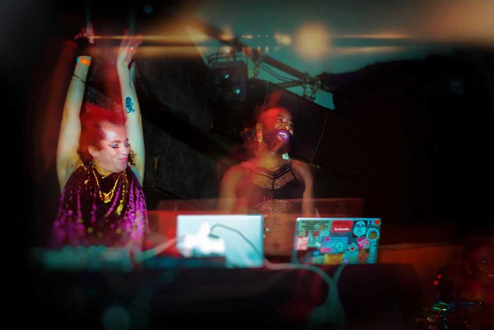 WIENWOCHE 2023: It’s so heating. Mzamo Nondlwana & Pêdra Costa posing in party outfits behind the DJ decks. © Doris Meixner